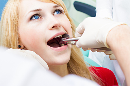 A woman receiving dental care with a dental hygienist assisting her during a dental appointment.