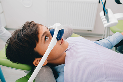 A young person sitting in a dental chair with a device over their eyes, likely for vision enhancement during a dental procedure.